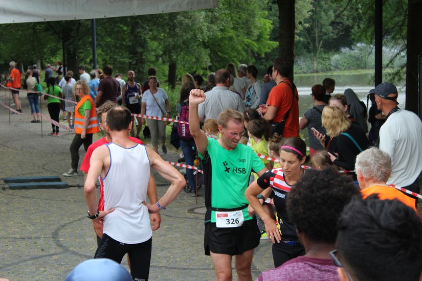 L&auml;ufer stehen auf der Strecke und an der Seite sind mehrere Zuschauer.