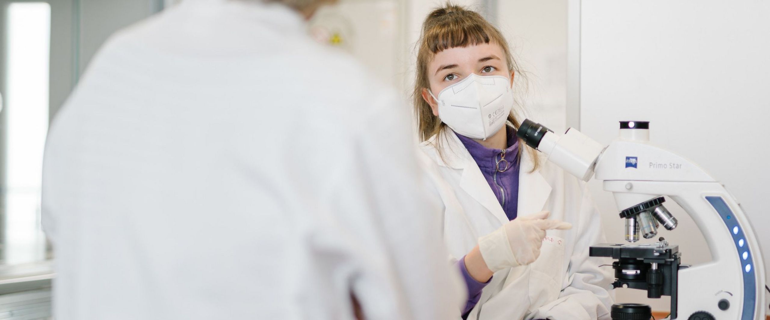 Studierende bei einem Versuch im Hygienepraktikum vor einem Mikroskop