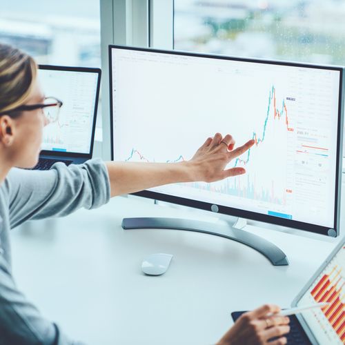 Frau vor einem Computerbildschirm zeigt auf Statistik