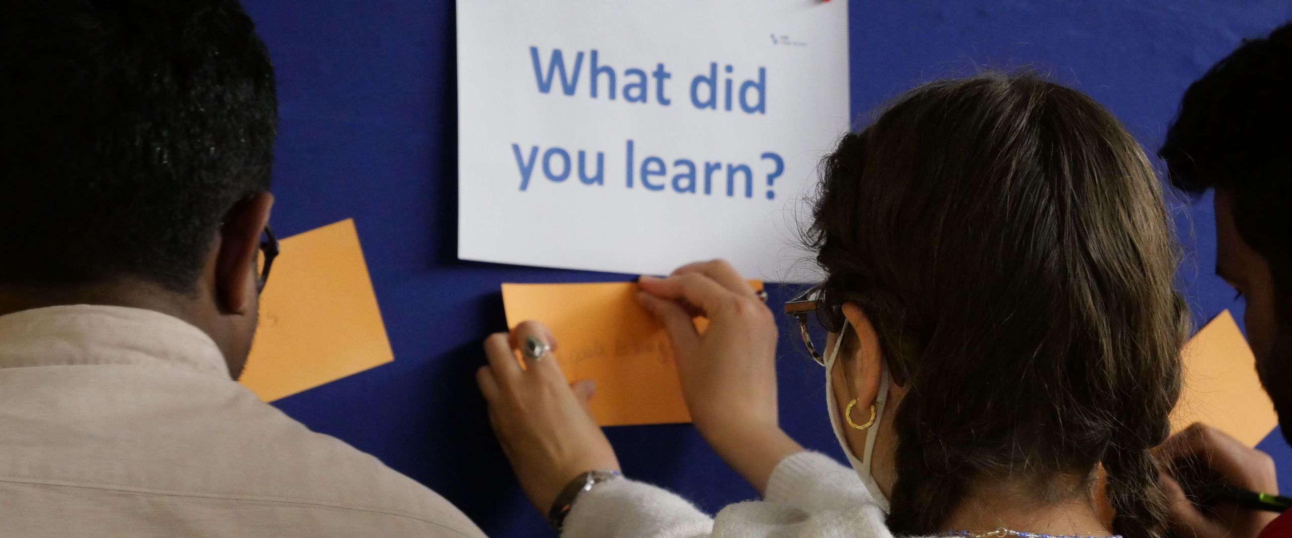 What did you learn? Zwei Studierende vor einer Tafel mit dieser Aufschrift