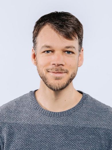 Auf dem Bild ist Peter Stegmaier zusehen. Er hat kurzes braunes Haar und einen Bart. Er trägt einen dunkelblauen Strickpullover.