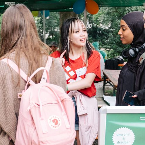 Anmeldung und Support beim meetMINT-Sommerfest 2023 3 Studentinnen melden sich bei einer Hilfskraft für das Sommerfest an.