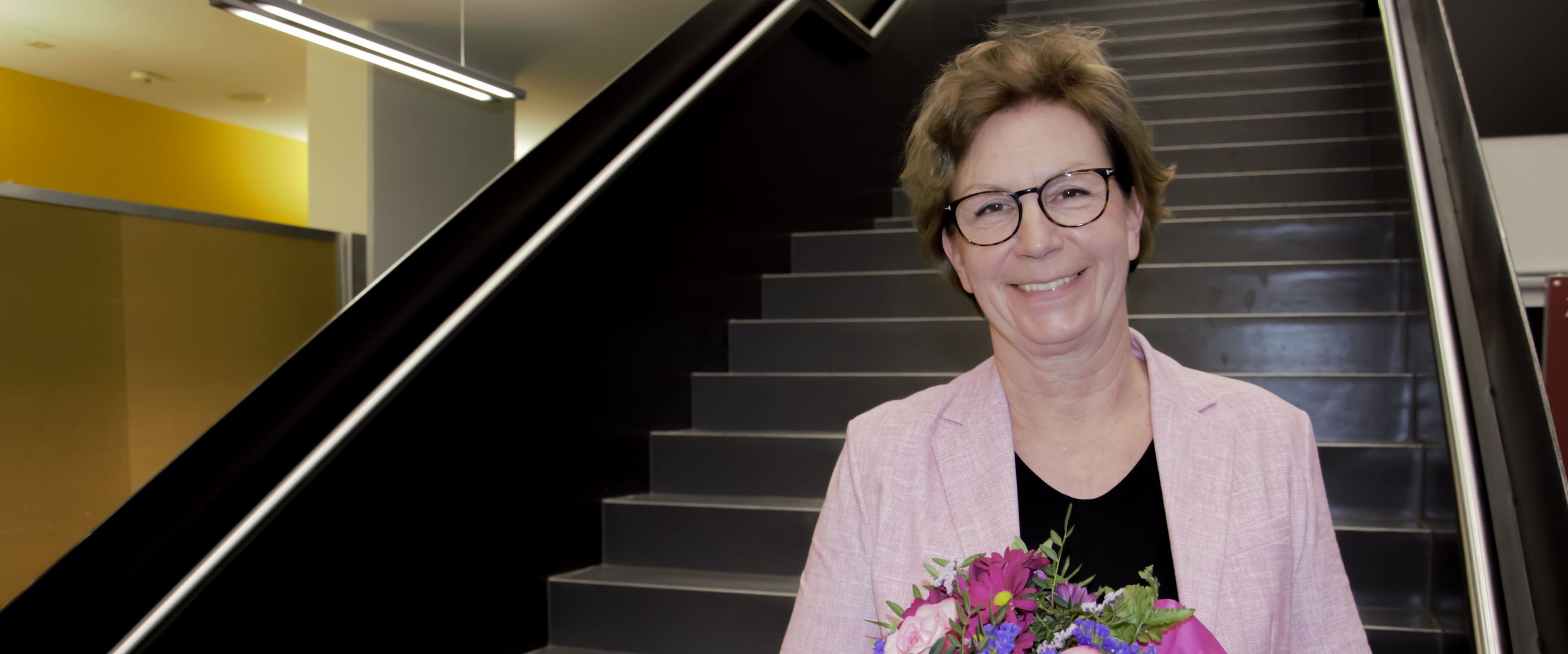  Woman with bouquet of flowers stands on stairs and laughs into the camera