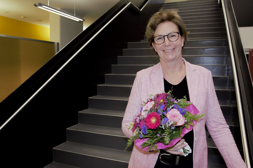  Woman with bouquet of flowers stands on stairs and laughs into the camera