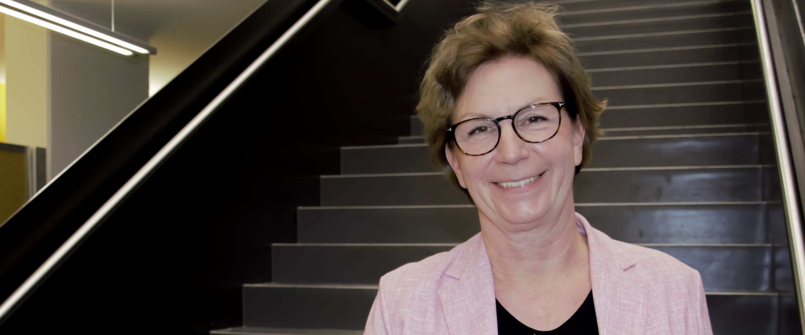 Bestellung Konrektorin Silke Eckardt Frau mit Blumenstrauß steht auf Treppe und lacht in die Kamera