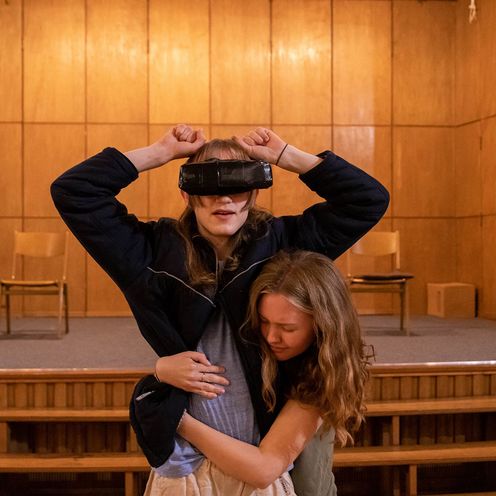 Eine junge Frau umarmt eine andere Frau, die eine Virtual-Reality-Brill tr&auml;gt, bei einer Probe der HSB-Theaterwerkstatt.