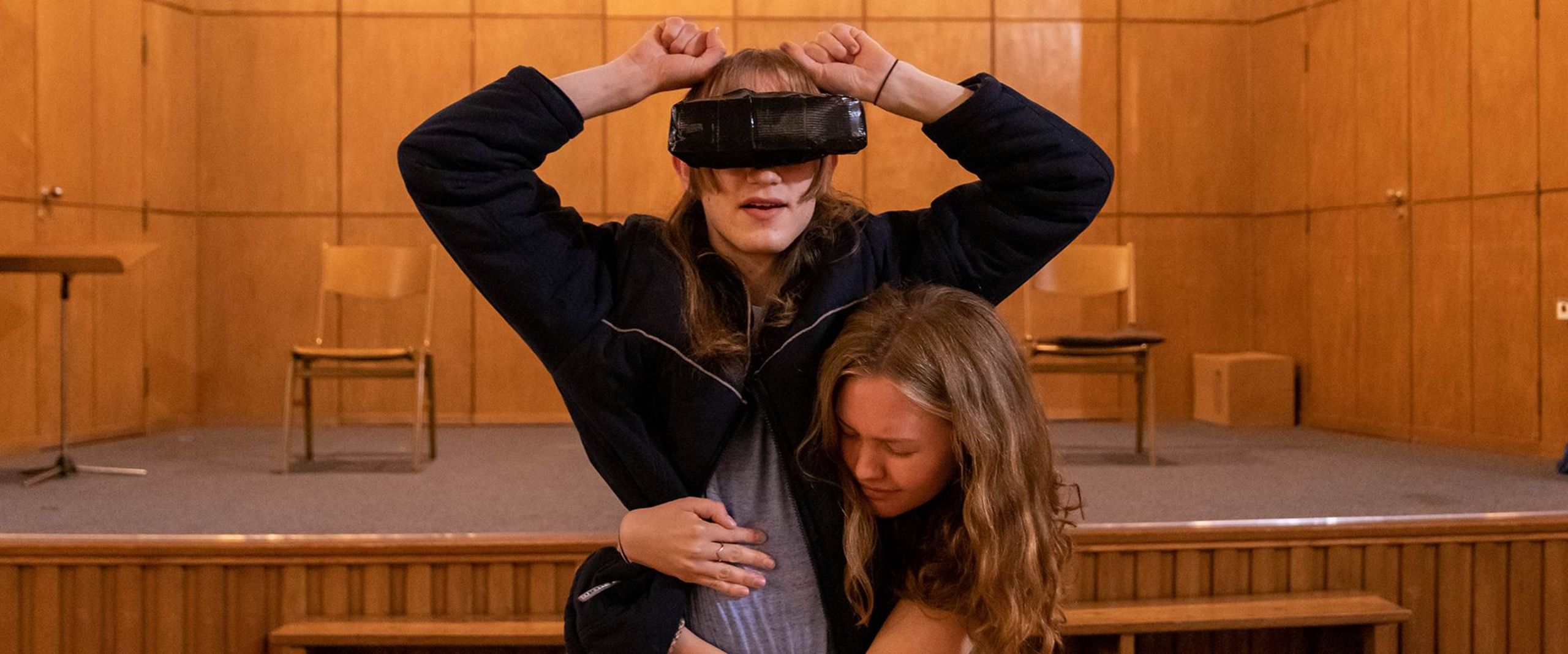 Eine junge Frau umarmt eine andere Frau, die eine Virtual-Reality-Brill trägt, bei einer Probe der HSB-Theaterwerkstatt.