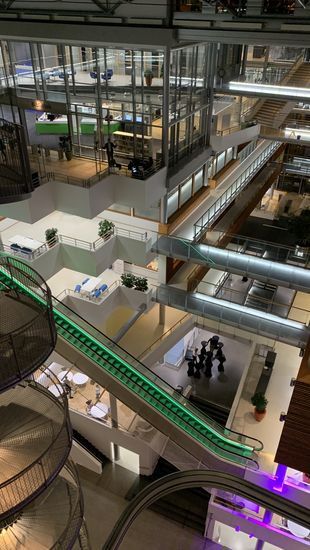 Man sieht das Gebäude der BI Norwegian Business University. Das Bild zeigt ein Foto von dem Foyer mit vielen verschiedenen Treppen und Rollentreppen, die bis zu sechs verschiedene Etagen mit einander verbinden. 