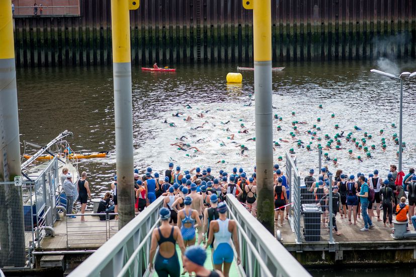 Taucher:innen laufen eine Br&uuml;cke runter Richtung Weser.