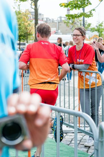 Ein L&auml;ufer auf der Strecke und eine l&auml;chelnde Zuschauerin.