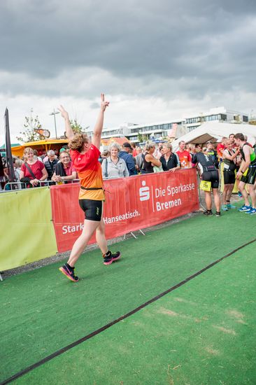 Ein jubelnder L&auml;ufer und an der Seite stehen mehrere Zuschauer.