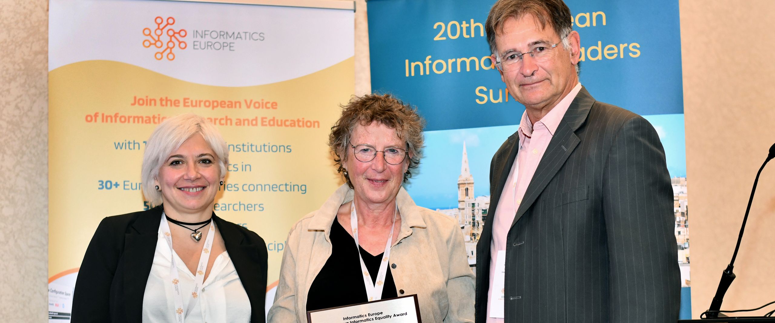 gruppenbild mit zwei Frauen und einem Mann. Die Frau in der Mitte hält eine Urkunde