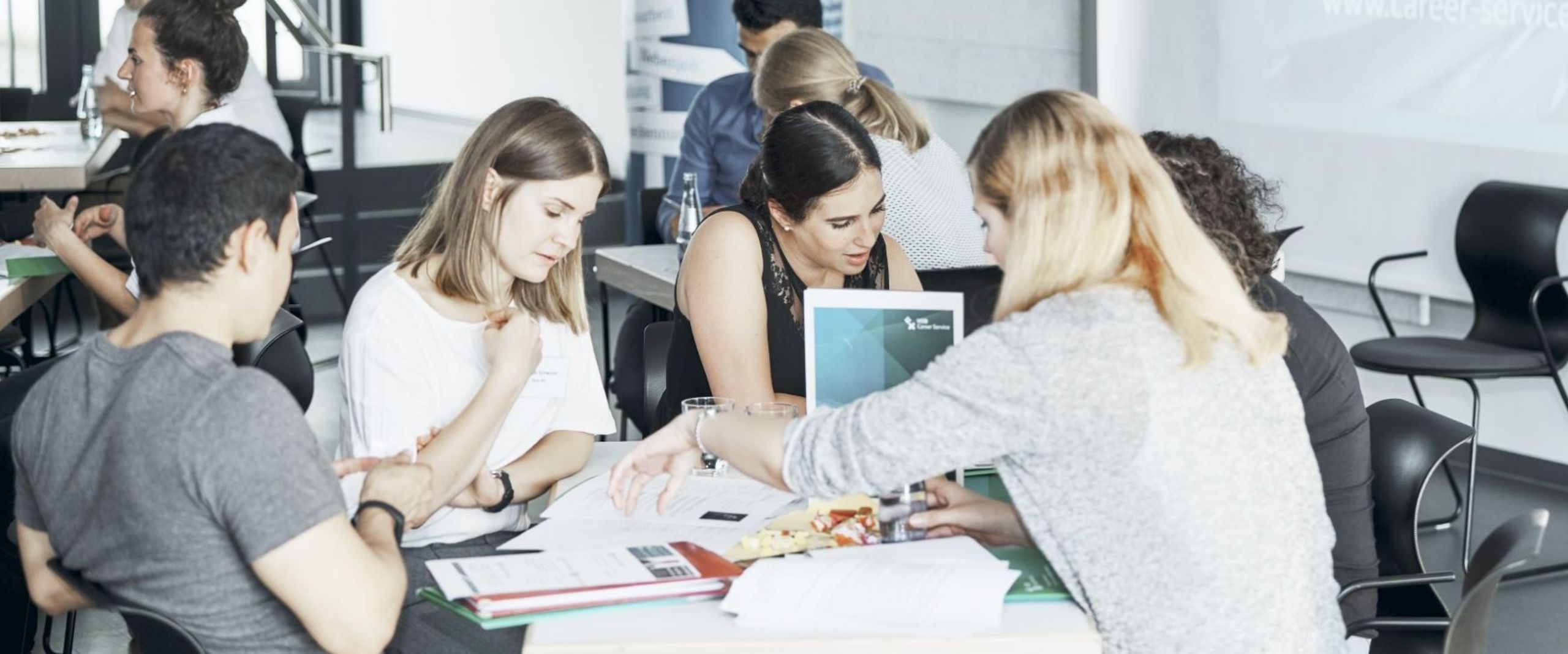 Teilnehmende der "Langen Nacht der Bewerbung" diskutieren an einem Tisch.