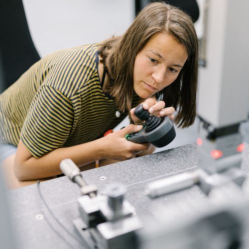 Eine Studentin bedient eine Maschine mit einer Steuereinheit.