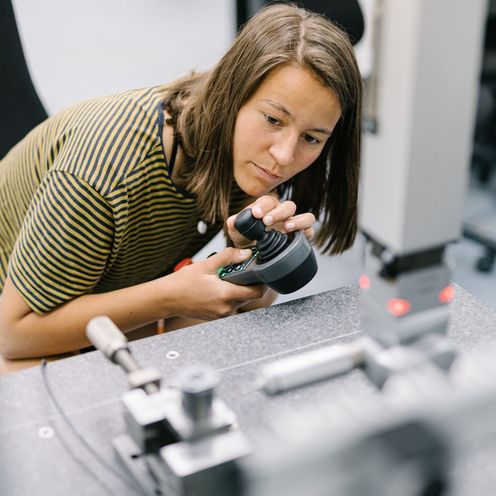 Eine Studentin bedient eine Maschine mit einer Steuereinheit.