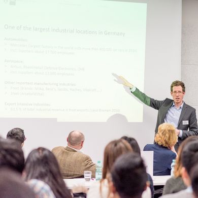 Ein Mann hält einen Vortrag vor Publikum.