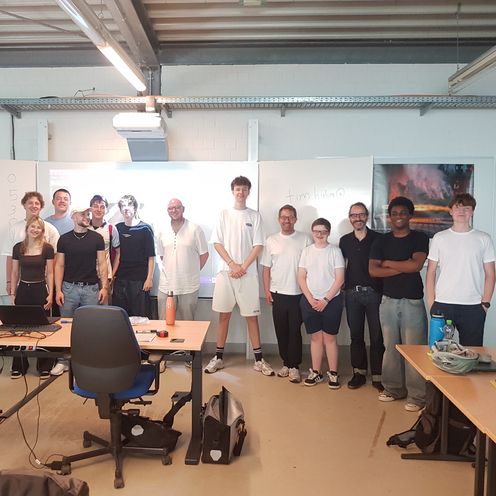 Sch&uuml;lerinnen und Sch&uuml;ler posieren zu Gruppenfoto vor Tafel