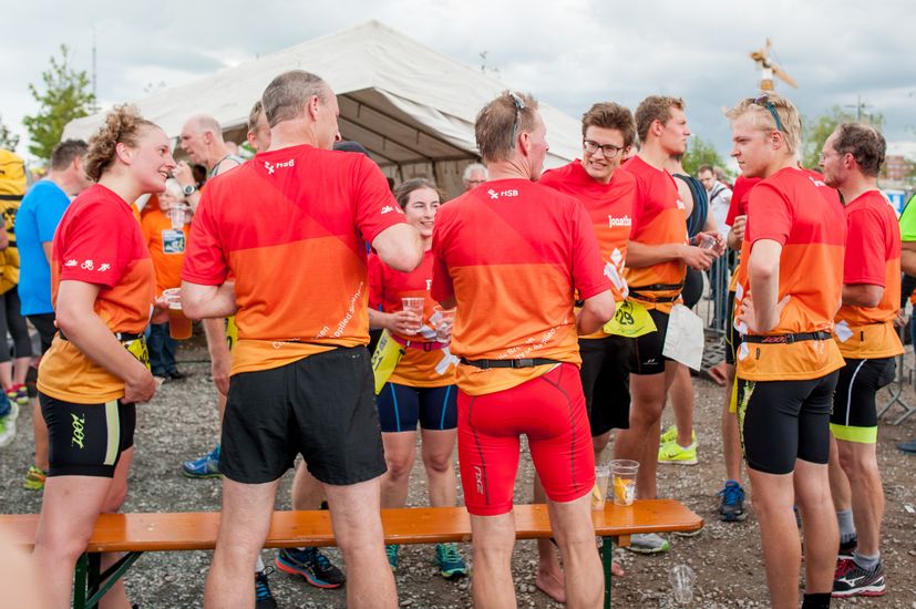 L&auml;ufer mit HSB Trikot stehen um eine Bank herum.