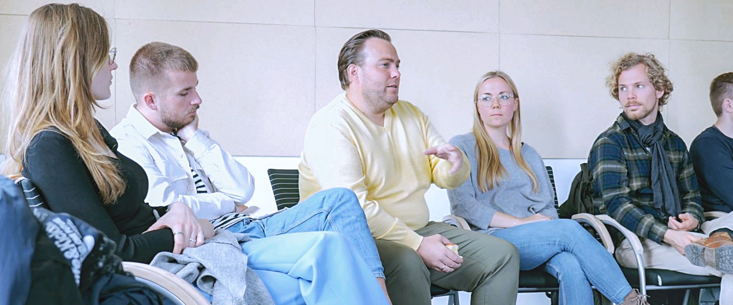 Bild mit M&auml;nnern und Frauen. Sie sitzen im Halbkreis zusammen und diskutieren.