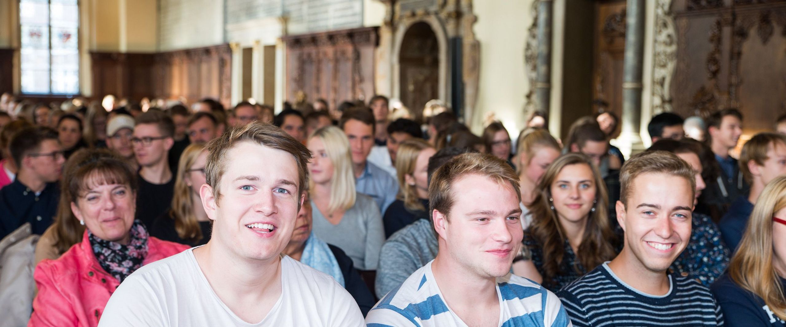 Studierende sitzen im Publikum bei der Begrüßung der Erstsemester in der Oberen Rathaushalle.