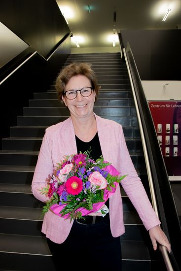 Woman with a bouquet of flowers laughs into the camera on a staircase
