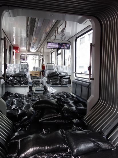Schwarze Säcke liegen auf Sitzen in einer Straßenbahn. Die Polster sind mit Plastikfolien abgedeckt.