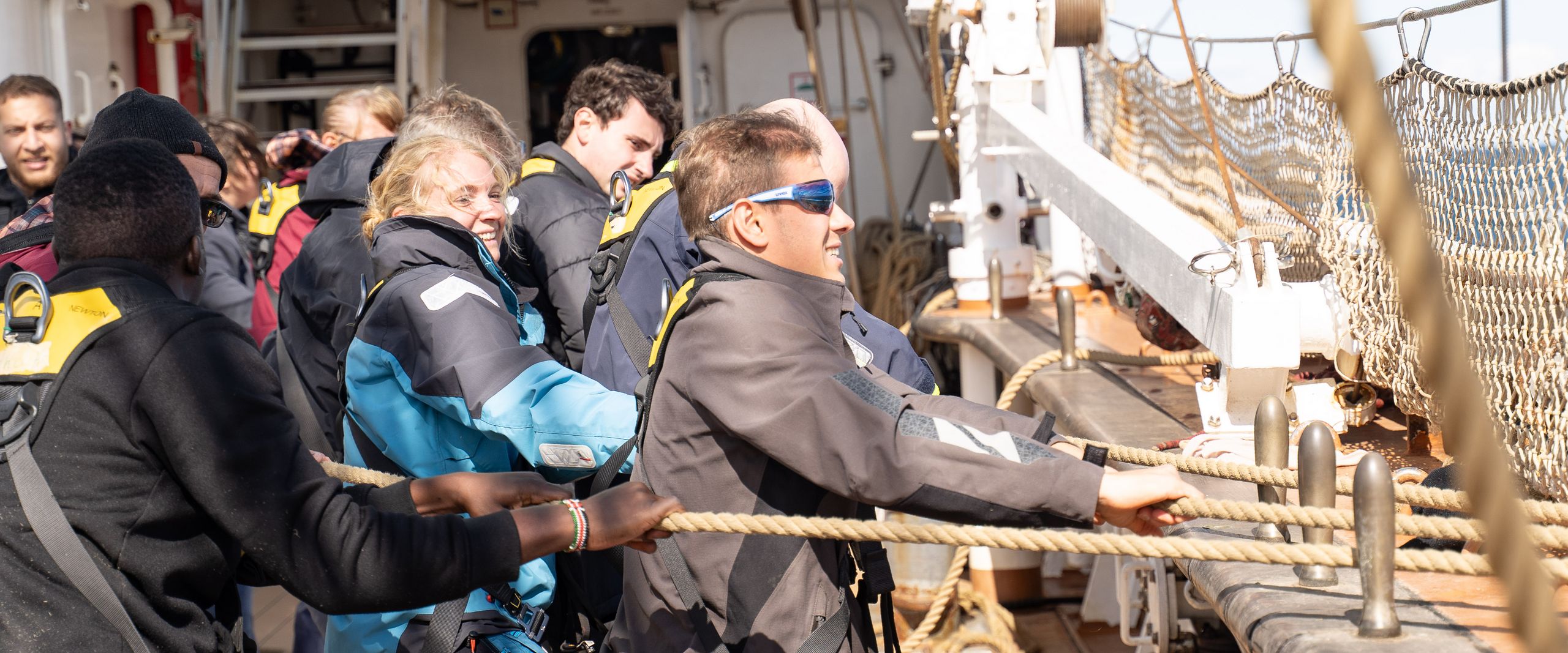 Segelmanöver Auf dem Bild sind Leute zu erkennen, die an Board eines Schiffes an Seilen ziehen.