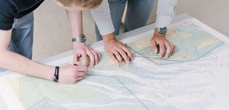 Nautikstudierende arbeiten mit einer Seeakarte.