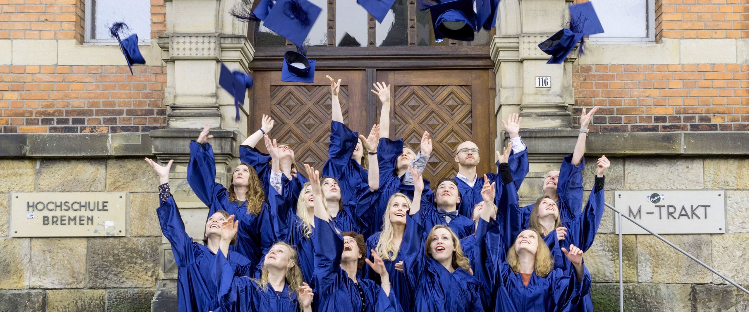 Absolvent:innen des Studiengangs Angewandte Therapiewissenschaften werfen Ihre Doktorhüte in die Luft.