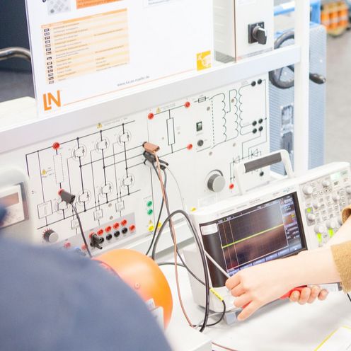 Veranstaltung des Studiengangs Elektrotechnik. Eine Studentin hantiert mit Kabeln an einem Ger&auml;t.