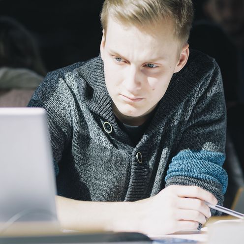 Junger Mann schaut auf den Bildschirm eines Laptops.