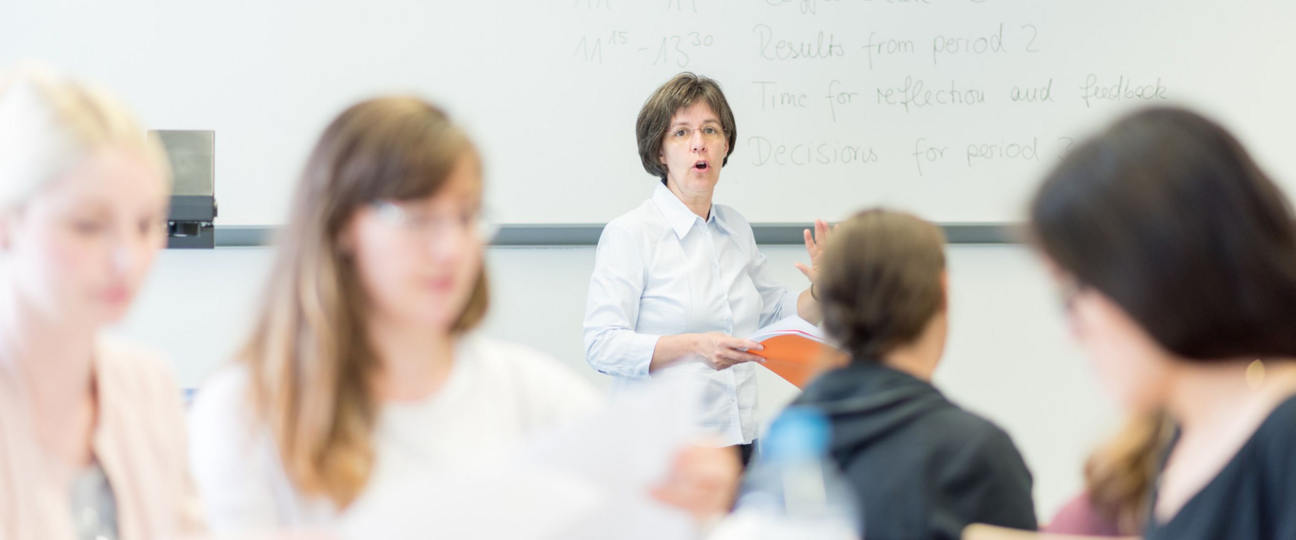 Studierende mit einer Professorin im Seminar.