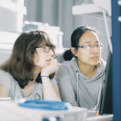 Studierende in einem Labor blicken auf einen Monitor.