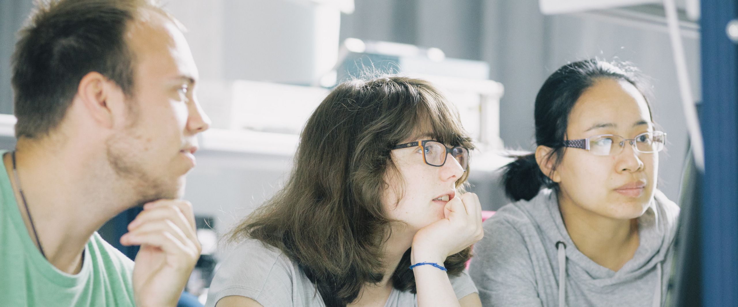 Studierende in einem Labor blicken auf einen Monitor.