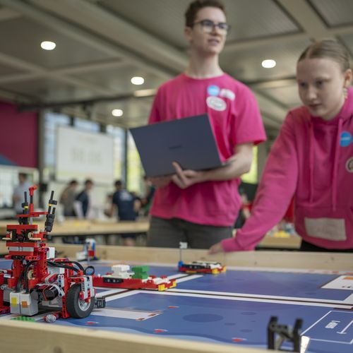 Zwei Personen steuern einen Roboter aus Klemmbausteinen 