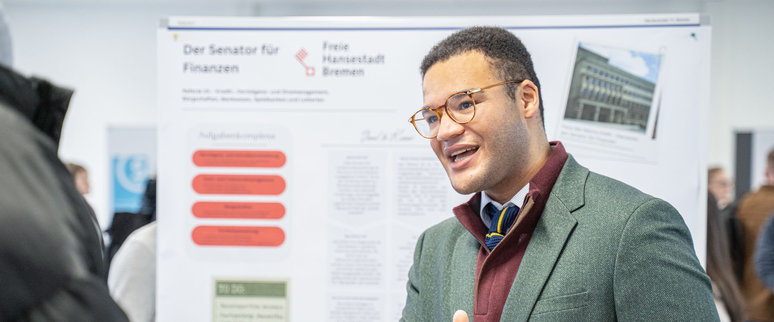 Mann gestikuliert vor einem Poster