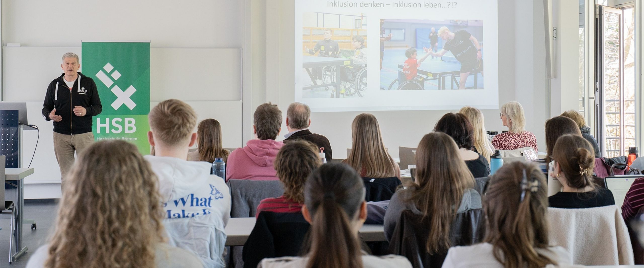 Das Bild zeigt Studierende, die einer Pr&auml;sentation zuh&ouml;ren.