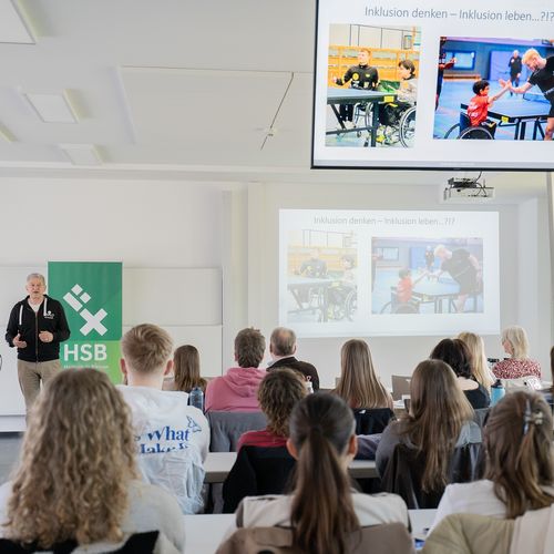 Das Bild zeigt Studierende, die einer Pr&auml;sentation zuh&ouml;ren.