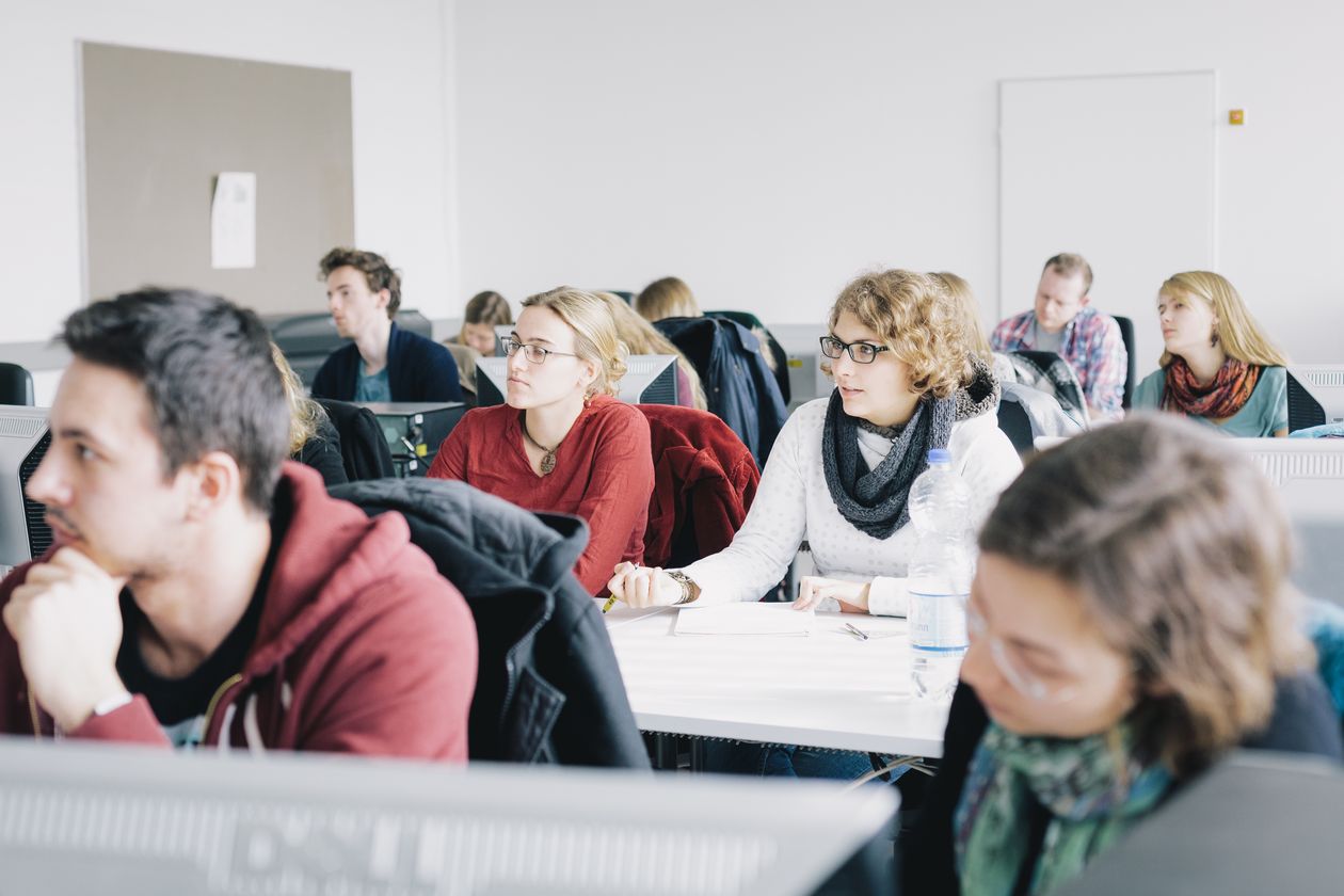 Junge Menschen sitzen in Seminarsaal und arbeiten