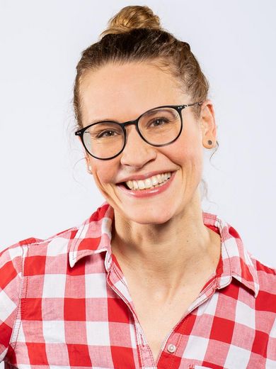 Auf dem Bild ist Ulrike Jacobs zusehen. Sie hat ihre blonden Haare zu einem Dutt zusammengesteckt. Sie tr&auml;gt eine Brille und eine rot-wei&szlig; karierte Bluse. 