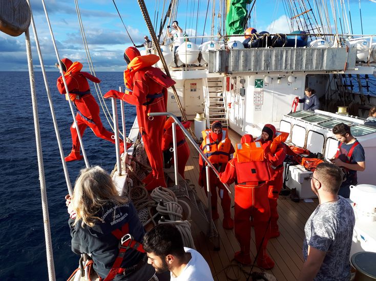 Nautikstudierende springen bei einer Übung in Neoprenanzügen von Bord des Segelschiffes Alexander von Humboldt II.