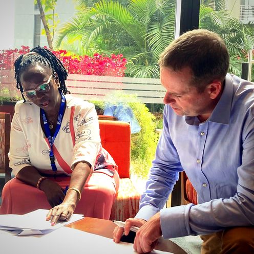 Prof. Dr. Rainer Lisowski sitzt neben Hon. Cicilia Namulen am Tisch.