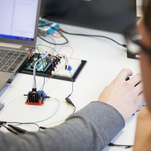 Person schaut einer anderen Person am Laptop bei einem Prozess zu.