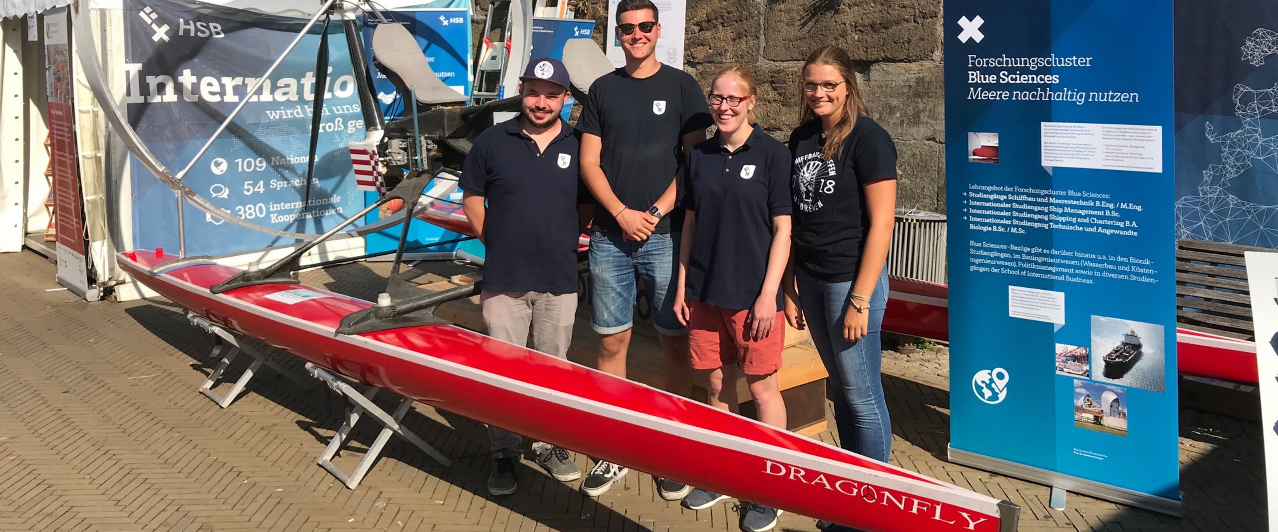 Forschungsmeile HSB Junge Menschen stehen vor einem roten Tretboot. Rechts steht ein Banner und hinter ihnen eine weiße Pagode.