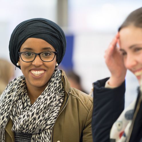 Studentin mit Kopftuch und Studentin mit langen, dunklen, hochgebundenen Haaren