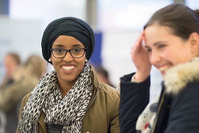 DSC-957520171107.jpg Studentin mit Kopftuch und Studentin mit langen, dunklen, hochgesteckten Haaren, beide fröhlich lachend