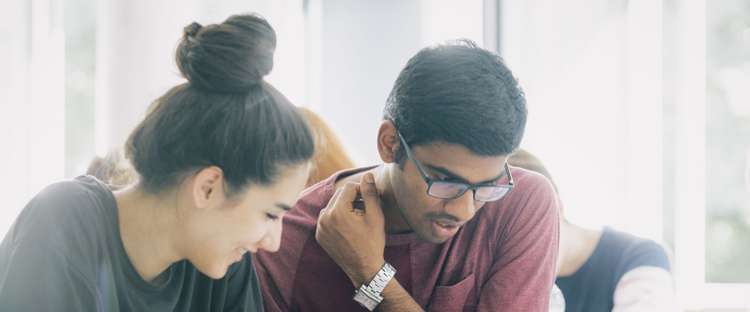 Eine Studentin und ein Student über Unterlagen gebeugt