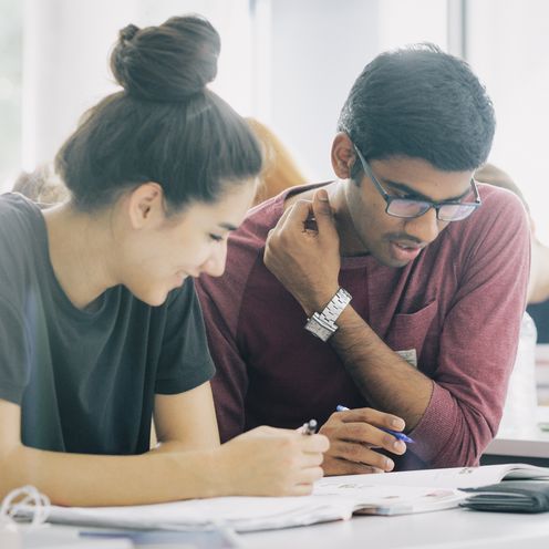 Eine Studentin und ein Student &uuml;ber Unterlagen gebeugt