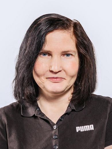 Auf dem Bild ist Janine Daum zusehen. Sie hat glattes, schulterlanges schwarzes Haar und trägt ein schwarzes Polo-Shirt. 
