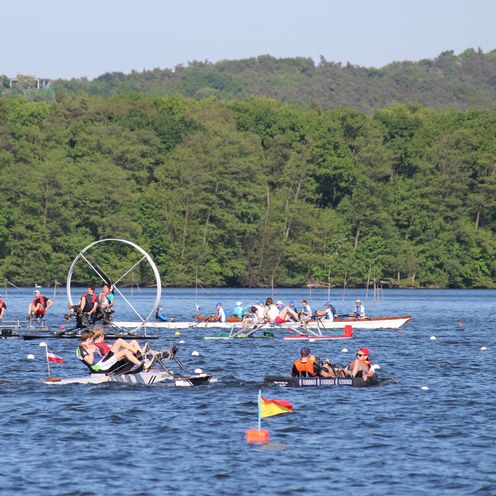 Studentische Tretbootteams bei einer Regatta auf einem See.